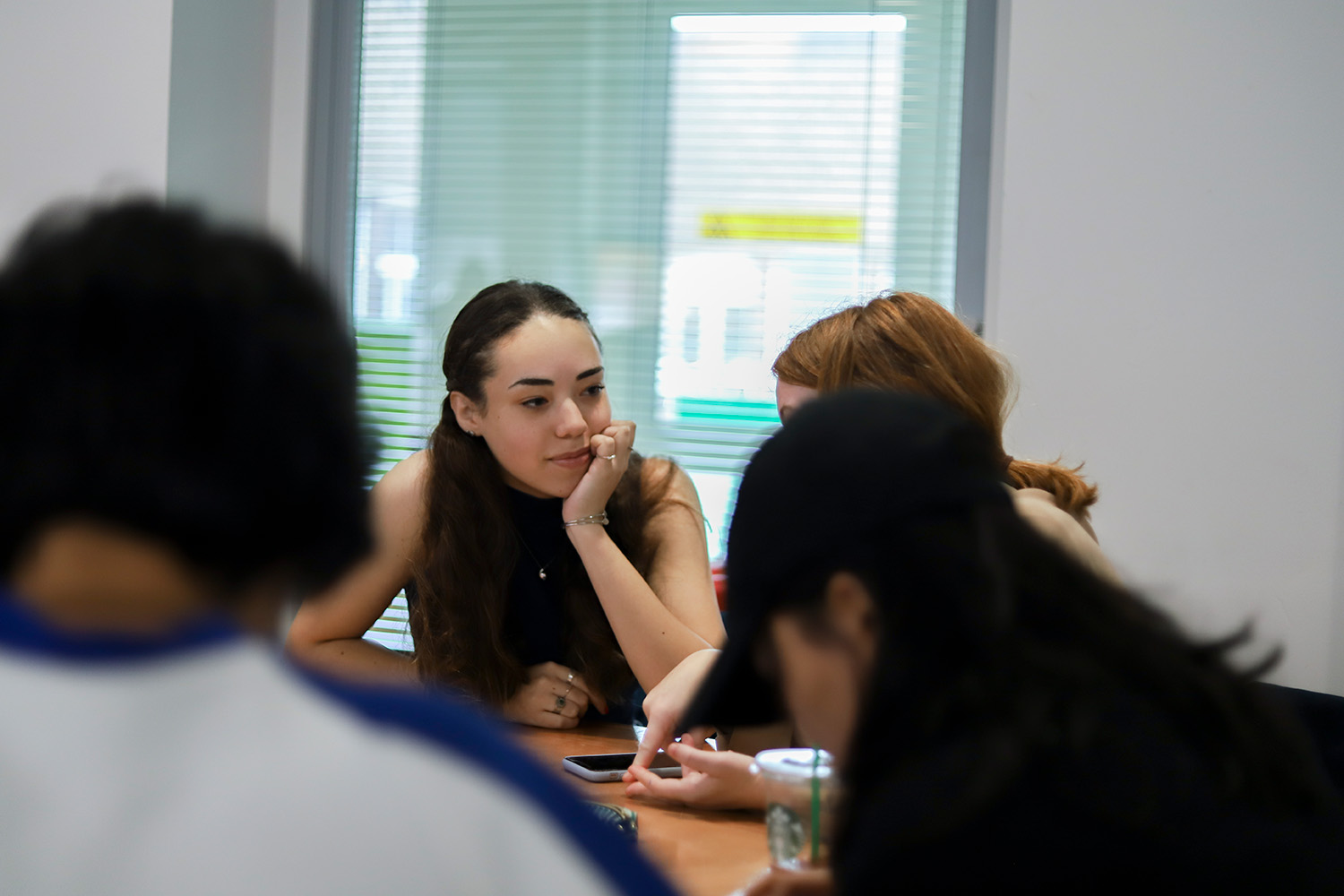 Student at a table listening to another student from the group